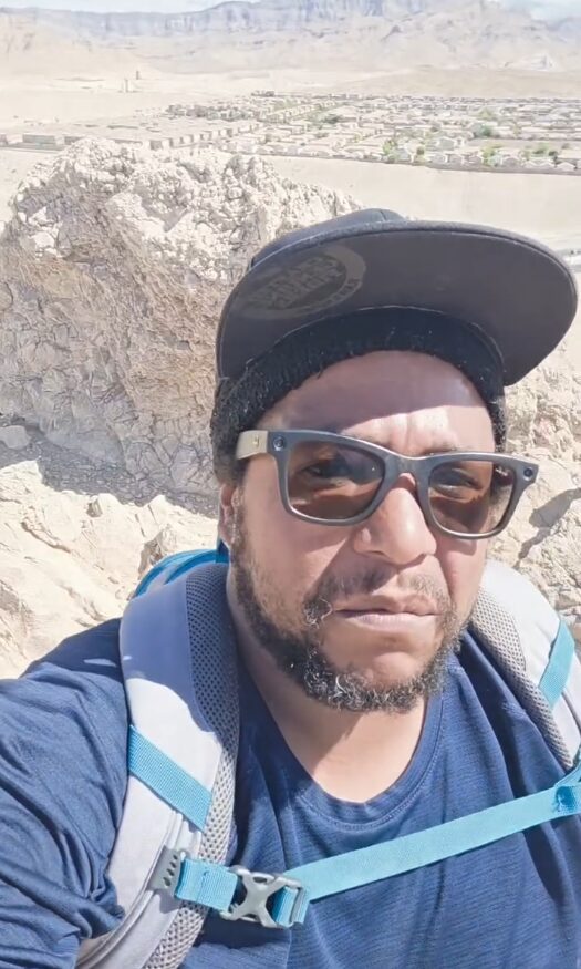 Rich in sunglasses and a cap at the top of Lone Mountain with the valley behind him