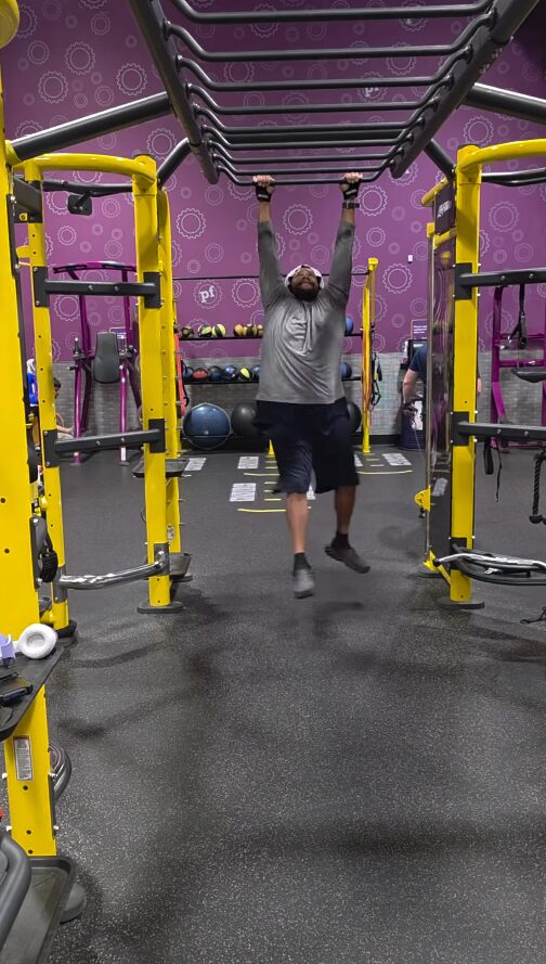 Rich hanging from the monkey bars in a gym
